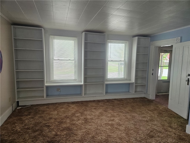 unfurnished room featuring dark carpet and built in shelves