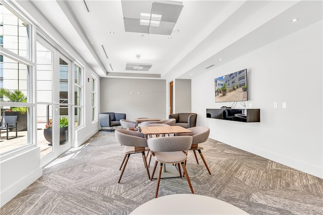 dining room featuring light carpet and a raised ceiling