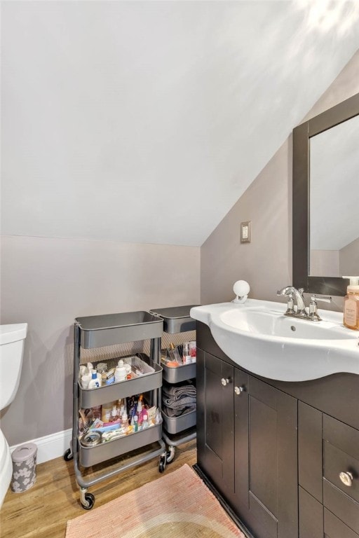 bathroom featuring vaulted ceiling, vanity, hardwood / wood-style flooring, and toilet