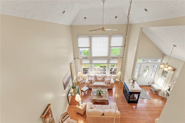 living room featuring a textured ceiling, light hardwood / wood-style floors, ceiling fan, and high vaulted ceiling