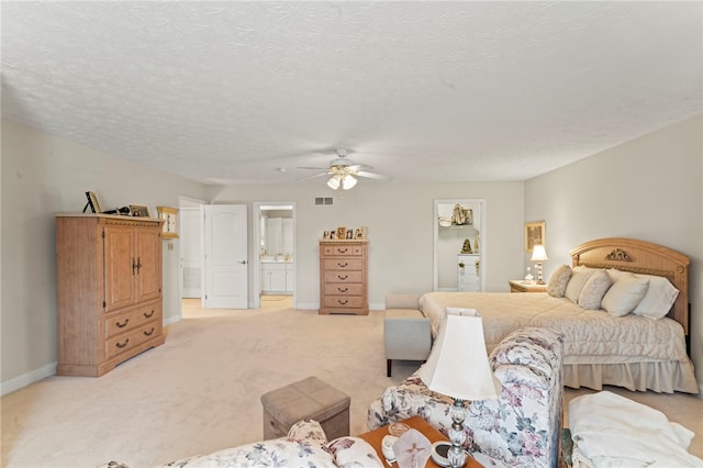 carpeted bedroom with a textured ceiling, connected bathroom, and ceiling fan