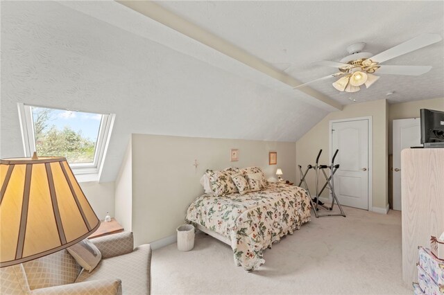 carpeted bedroom with lofted ceiling with skylight and ceiling fan