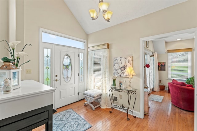 foyer featuring hardwood / wood-style flooring, vaulted ceiling, a chandelier, and plenty of natural light