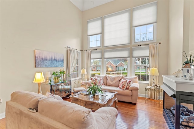 living room featuring a multi sided fireplace, light wood-type flooring, and a high ceiling