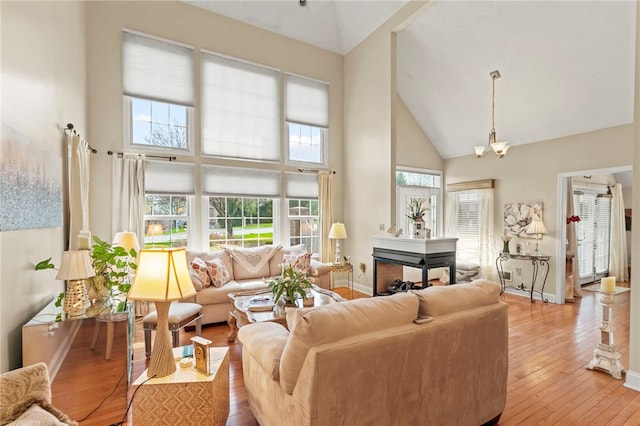 living room featuring a notable chandelier, light hardwood / wood-style flooring, and high vaulted ceiling