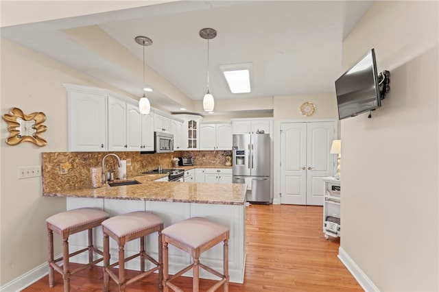 kitchen featuring sink, kitchen peninsula, light hardwood / wood-style flooring, stainless steel appliances, and decorative backsplash