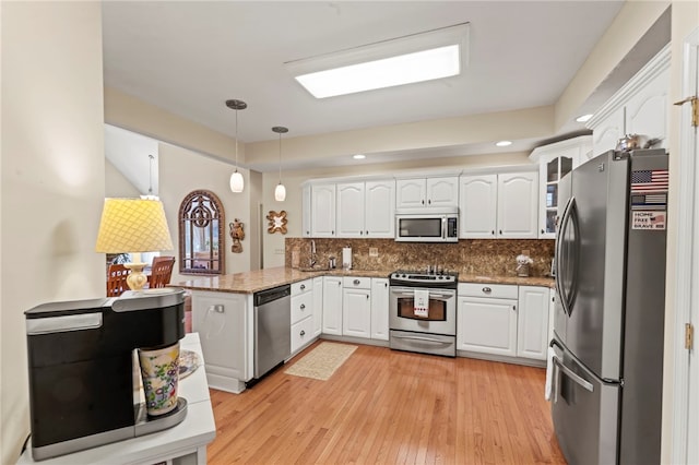 kitchen with pendant lighting, white cabinetry, stainless steel appliances, light wood-type flooring, and decorative backsplash