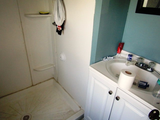 bathroom with a shower and vanity with extensive cabinet space