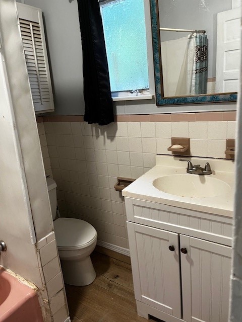 full bathroom featuring tile walls, backsplash, toilet, wood-type flooring, and vanity