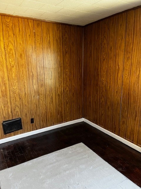 empty room featuring dark hardwood / wood-style flooring and wooden walls