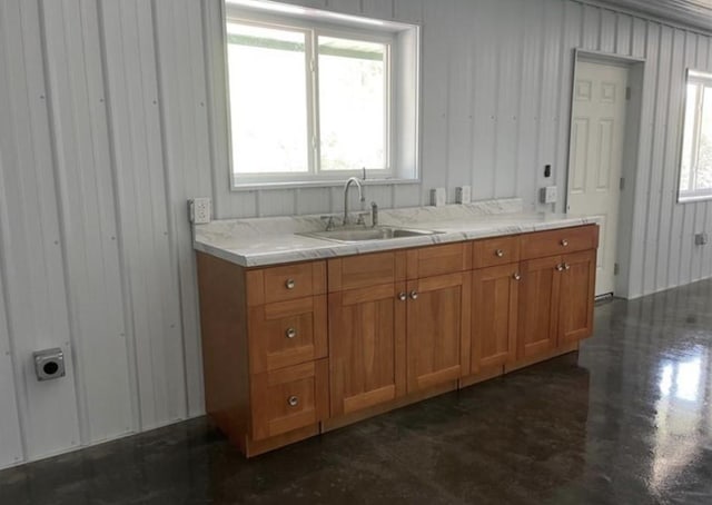 kitchen with a healthy amount of sunlight, brown cabinetry, light countertops, and a sink