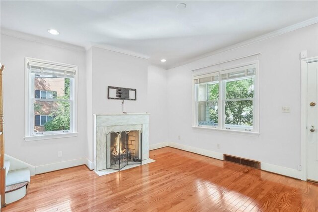 unfurnished living room featuring a premium fireplace, crown molding, and light hardwood / wood-style flooring