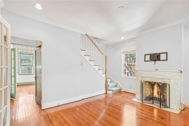 unfurnished living room featuring stairs, hardwood / wood-style floors, a fireplace, and baseboards