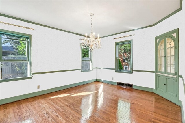 spare room featuring crown molding, a notable chandelier, and wood-type flooring