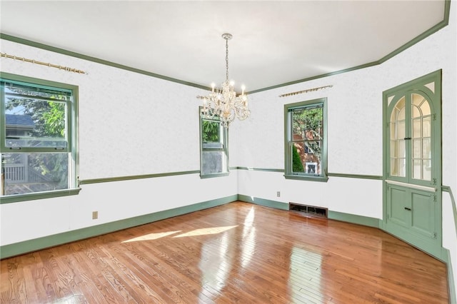 spare room featuring ornamental molding, wood-type flooring, visible vents, and plenty of natural light