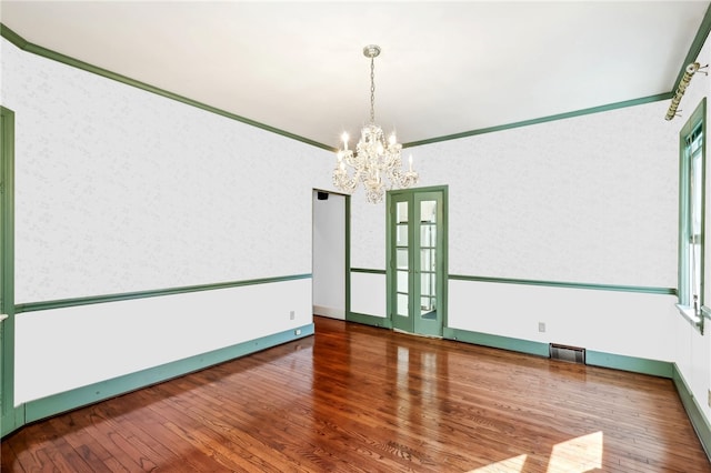 unfurnished room featuring crown molding, dark hardwood / wood-style flooring, and a notable chandelier