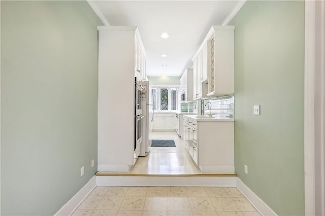 hall with recessed lighting, a sink, and baseboards