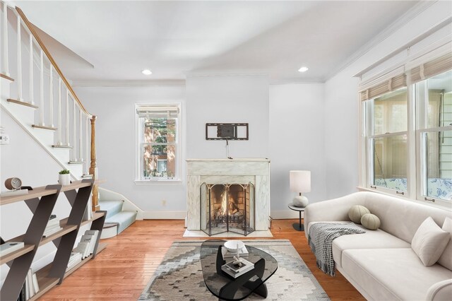 living room with ornamental molding, wood-type flooring, and a high end fireplace