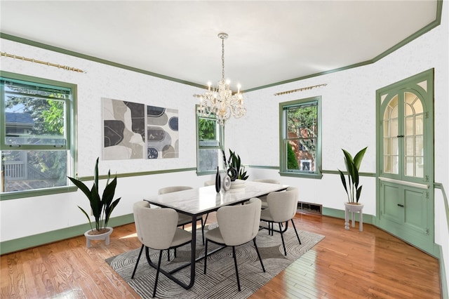 dining area featuring a notable chandelier, visible vents, ornamental molding, wood finished floors, and baseboards