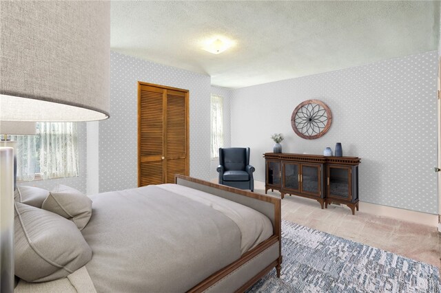 bedroom with wallpapered walls, a textured ceiling, a closet, and carpet flooring