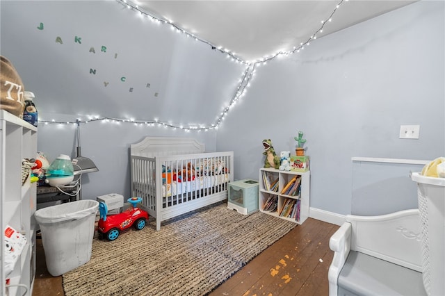 bedroom with dark hardwood / wood-style flooring and a nursery area