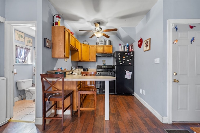 kitchen with ceiling fan, a breakfast bar, tile floors, black appliances, and kitchen peninsula