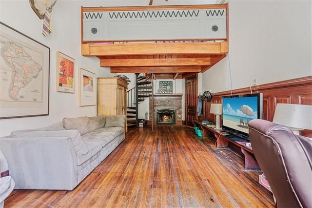 living room with beam ceiling, hardwood / wood-style flooring, a fireplace, and a high ceiling