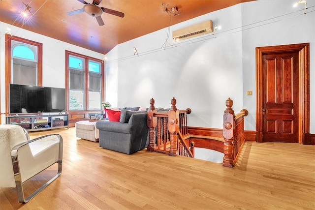 living room with lofted ceiling, light hardwood / wood-style floors, ceiling fan, and a wall unit AC