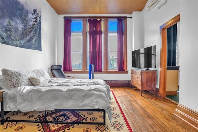 bedroom featuring wood ceiling, a wall unit AC, and hardwood / wood-style flooring