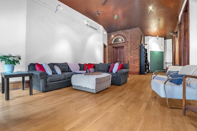 living room featuring brick wall and light hardwood / wood-style flooring