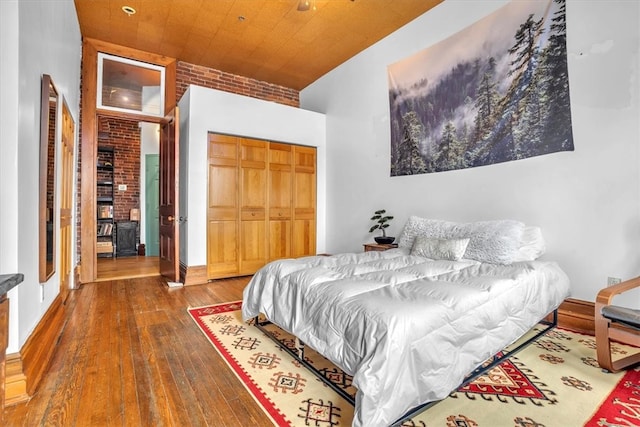 bedroom featuring a closet, brick wall, and dark hardwood / wood-style floors