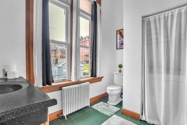 bathroom with tile flooring, vanity, toilet, and radiator