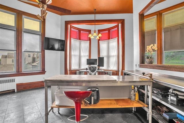 interior space featuring radiator heating unit, a notable chandelier, stainless steel counters, dark tile flooring, and hanging light fixtures