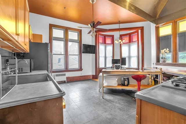 kitchen with stainless steel counters, hanging light fixtures, ceiling fan with notable chandelier, tile floors, and radiator heating unit