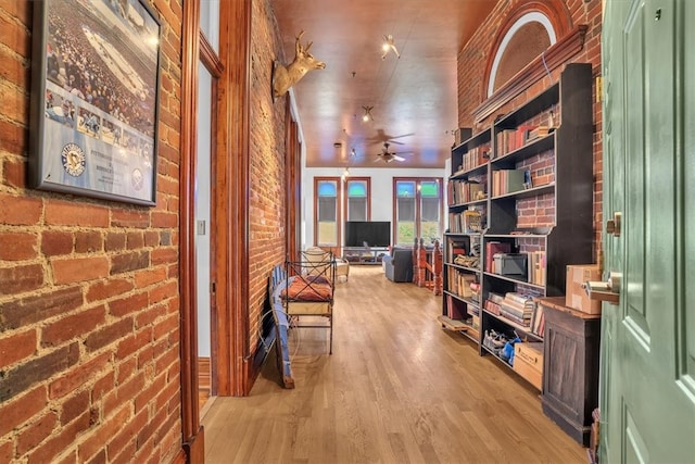 hall featuring brick wall and light hardwood / wood-style flooring