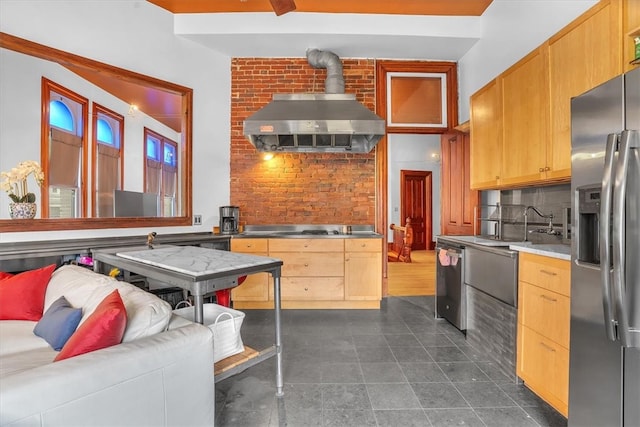 kitchen with wall chimney exhaust hood, dark tile flooring, backsplash, brick wall, and stainless steel appliances