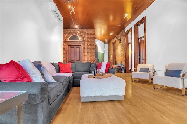 living room featuring hardwood / wood-style flooring, an AC wall unit, and brick wall