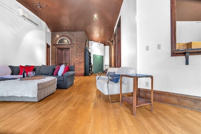 living room featuring vaulted ceiling, light hardwood / wood-style floors, and brick wall