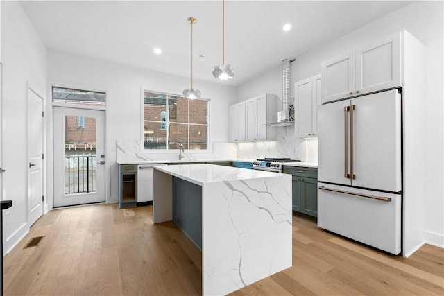 kitchen featuring pendant lighting, sink, light hardwood / wood-style flooring, a center island, and high quality appliances