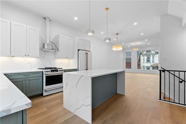 kitchen with white cabinetry, gas stove, a kitchen island, decorative light fixtures, and high end refrigerator