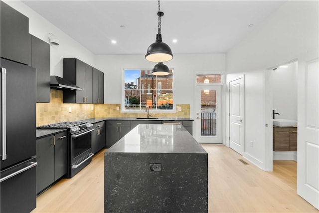 kitchen featuring high end fridge, hanging light fixtures, dark stone countertops, stainless steel range with gas stovetop, and a kitchen island