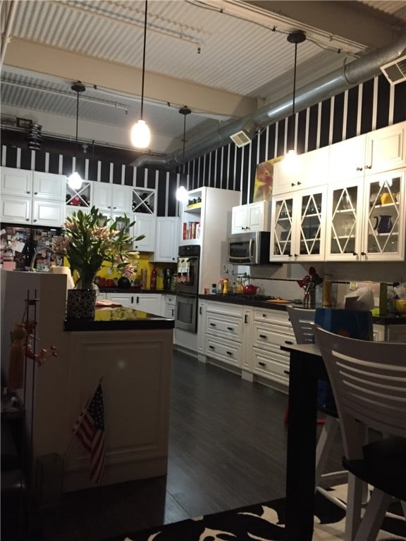 kitchen featuring white cabinetry, pendant lighting, a high ceiling, double oven, and dark hardwood / wood-style floors