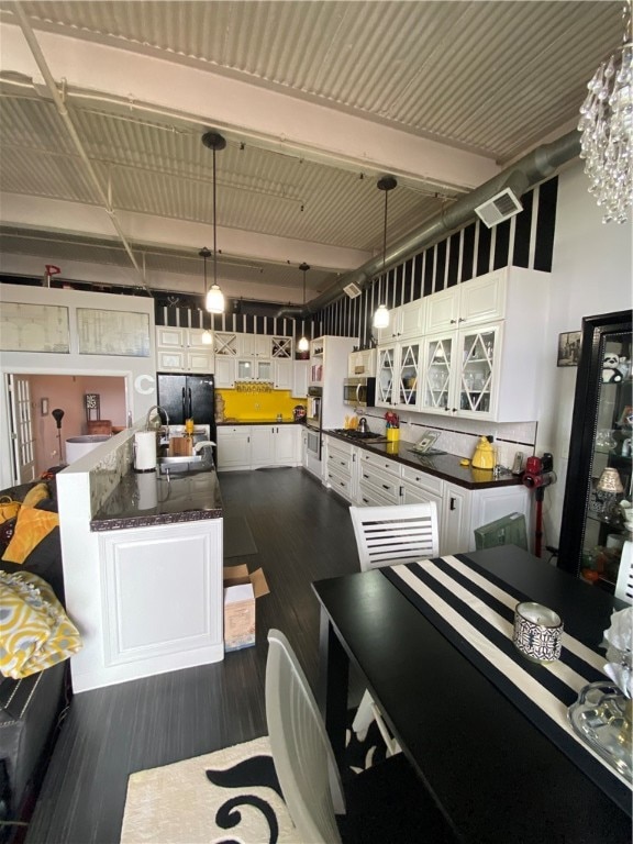 kitchen with white cabinets, dark hardwood / wood-style flooring, pendant lighting, black refrigerator, and beam ceiling