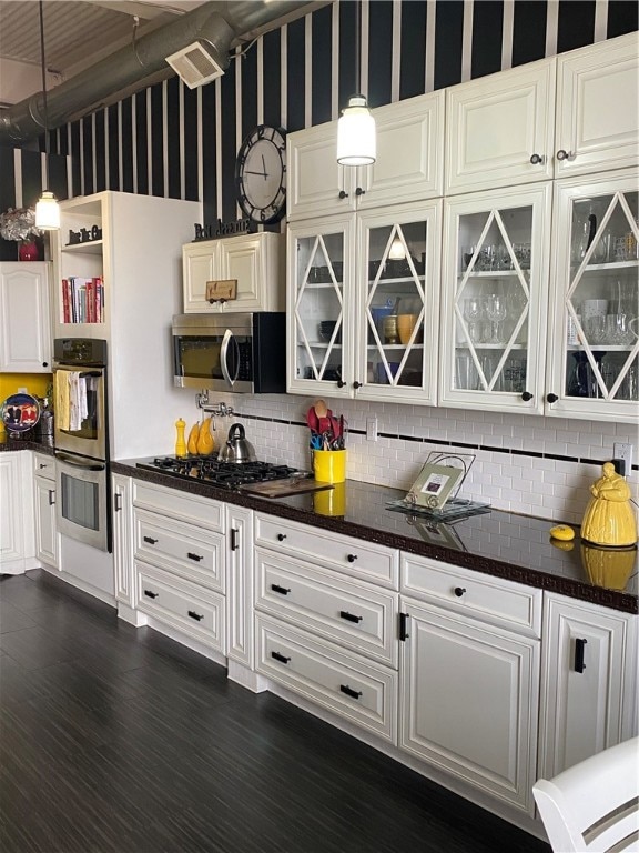 kitchen with stainless steel appliances, white cabinets, hanging light fixtures, and dark hardwood / wood-style flooring