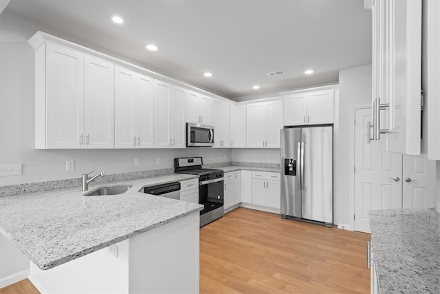 kitchen featuring white cabinetry, kitchen peninsula, stainless steel appliances, sink, and light hardwood / wood-style floors