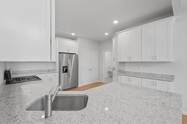 kitchen with white cabinets, stainless steel fridge, range, and light wood-type flooring