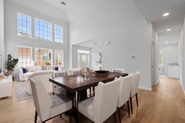 dining area featuring light hardwood / wood-style floors and high vaulted ceiling