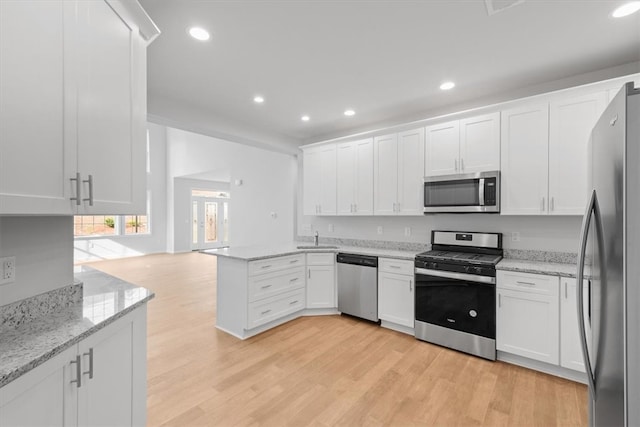 kitchen featuring appliances with stainless steel finishes, white cabinets, and light wood-type flooring