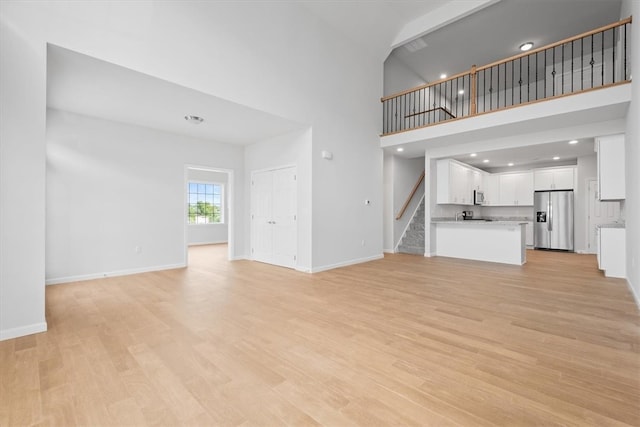 unfurnished living room featuring a high ceiling and light wood-type flooring