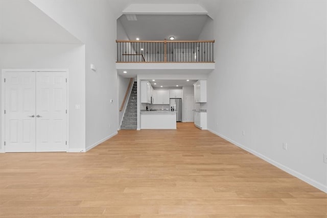 stairs with light hardwood / wood-style flooring and a towering ceiling